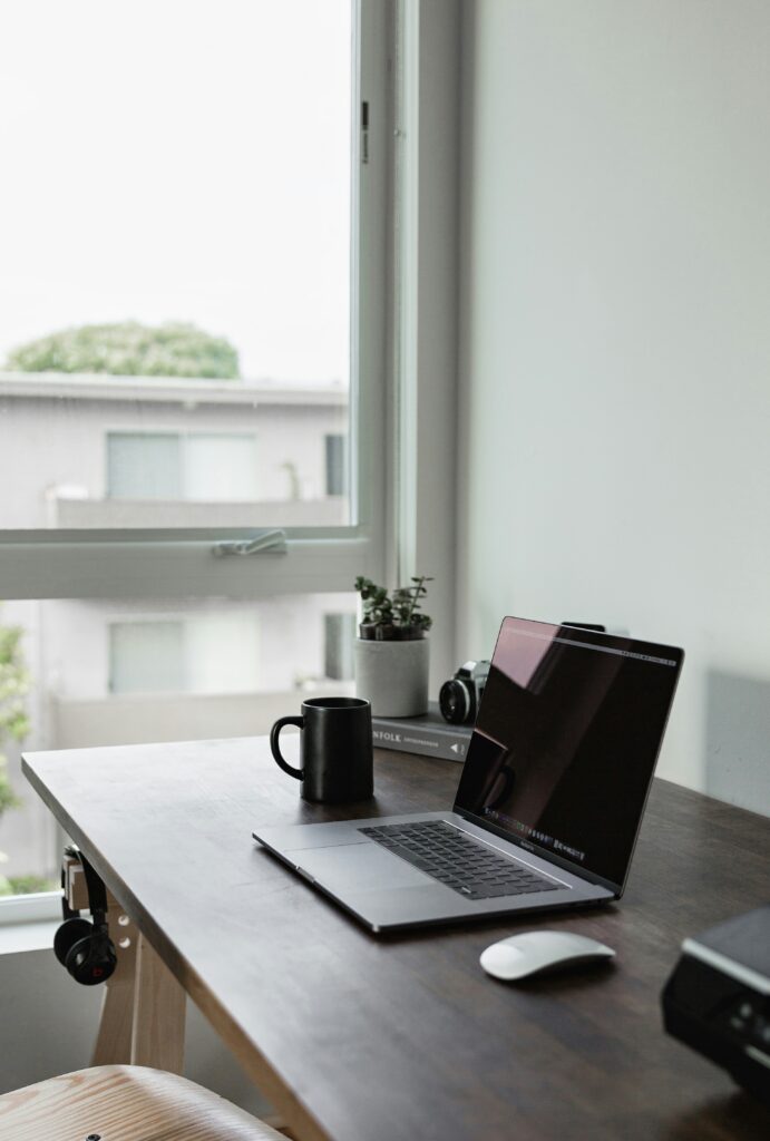 Bureau sobre et bien rangé sur lesquels sont posés un ordinateur et une tasse de café